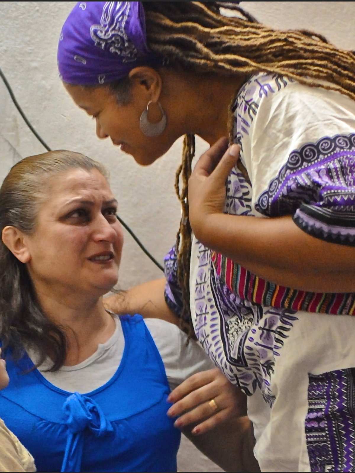 Amikaeyla leaning close to a woman in an intimate one-on-one healing session